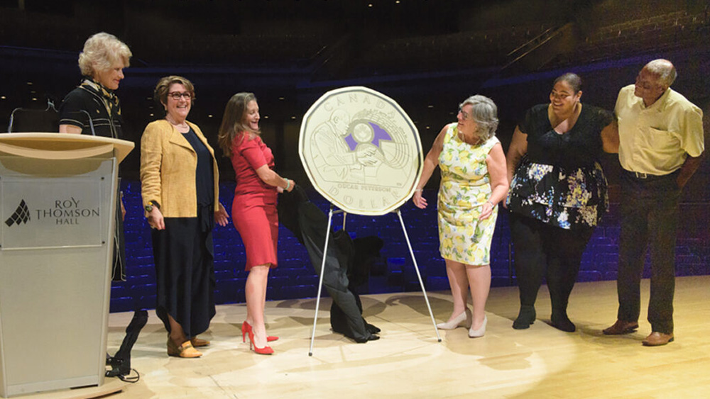Photo of a coin reveal with people on stage. Photo of a coin reveal with people on stage.