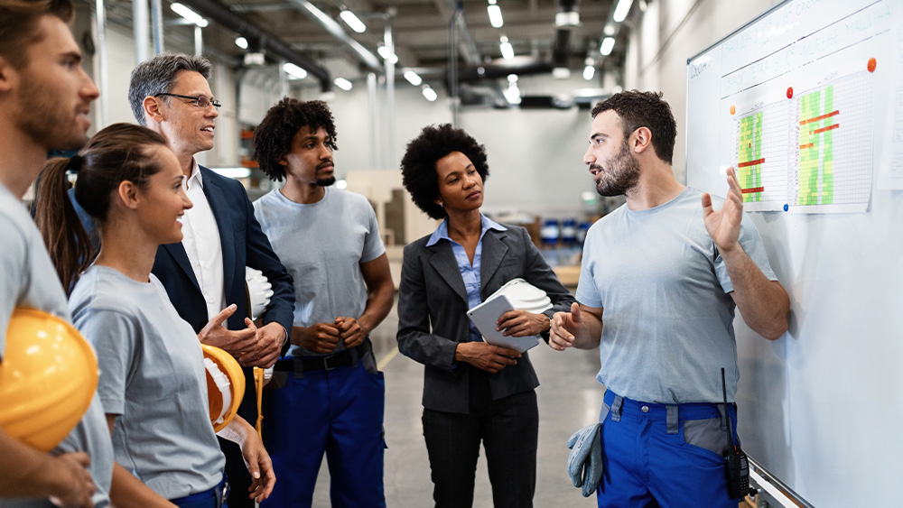 Photo of a group of people reviewing a whiteboard. Photo of a group of people reviewing a whiteboard.